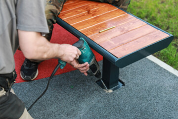 Blur image of installation of benches on the playground. Bench and holes on artificial grass for...