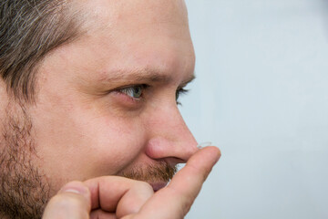 Man holds rigid lens on finger on light background. Fixing and use of contact lenses