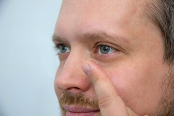 Man holds rigid lens on finger on light background. Fixing and use of contact lenses