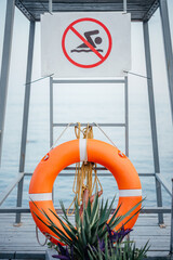 No swimming sign and orange lifebuoy at the beach during the storm