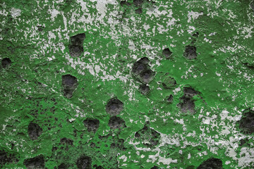 The wall of the metal garage, painted in green. Peeling paint on an old surface with rusty stains