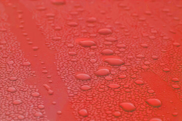 Water drops of morning dew on a  car hood, smooth surface. Set of condensation droplet  on a red...