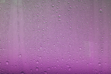 Water drops of morning dew on window glass, smooth surface. Set of condensation droplet  on a violet Background. Texture, abstract background, backdrop