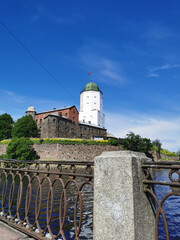 View from the embankment of the Vyborg Castle and the St. Olaf Tower, built in the 13th century, in the city of Vyborg against the blue sky.