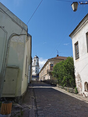A cobblestone street leading to the Clock Tower, a former bell tower, in the city of Vyborg against the blue sky.