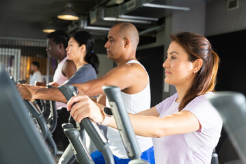 Athletic people running on elliptical trainer in a fitness club