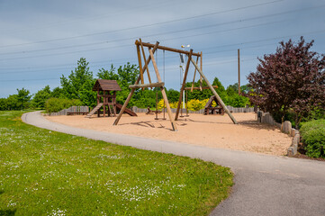 Fototapeta premium Children's playground equipped with wooden swings and slides. A modern children's slide made of wood and natural materials.