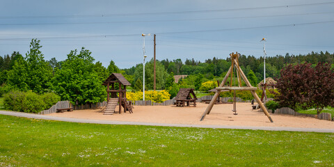 Children's playground equipped with wooden swings and slides. A modern children's slide made of...