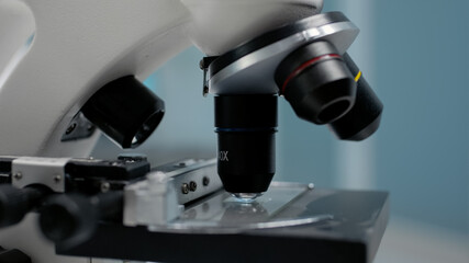 Close up of microscopic sample glass tray in laboratory. Microscope for optical test analysis with magnifying lens used in dna and bacteria research investigation and lab industry
