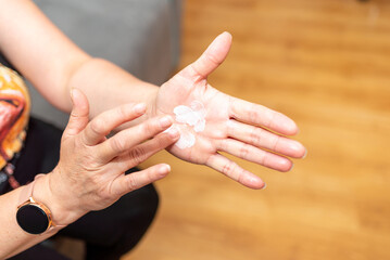 Womans hands applying moisturizer on her skin. Female smears hand cream at home, closeup.hands with a leaving cosmetic cream for a youth and elasticity of a skin. personal care. minimalism concept.