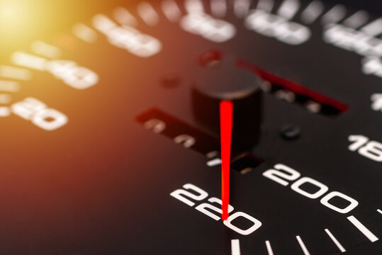 Car speedometer. Auto car speedometer shows 220 km h or miles.Closeup shot,dark black background.Automobile dangerous speed concept