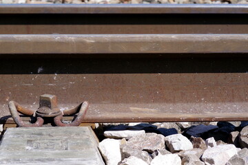 Nahaufnahme von Eisenbahnschienen mit Befestigung auf Schotterbett