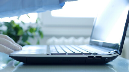 Closeup Image with Hands Wearing Protective Gloves Using the Laptop Keypad