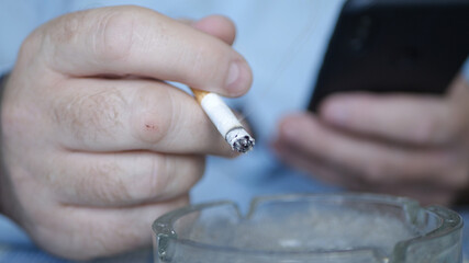 Businessman Smoking a Cigarette, Text Using a Mobile Phone. Relaxed Person Using a Cellphone and Smoking.