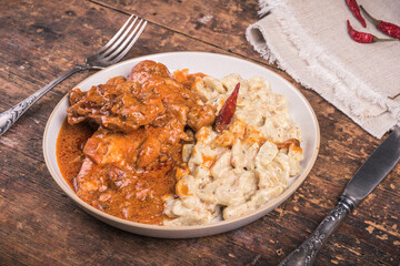 Portion of chicken stew with paprika and sour cream, chicken paprikash with gnocchi, dumplings on a plate