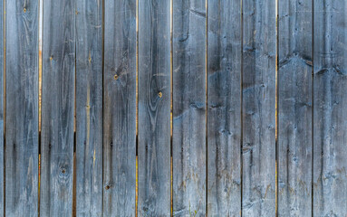 Texture of an old, darkened and cracked wood surface. Old rustic fence made of boards.