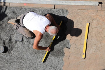 a worker is laying paving stones in gravel 