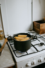 cooking the corn at the saucepan on the kitchen