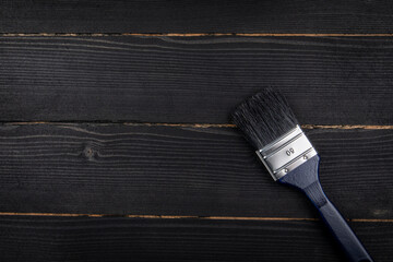 Paintbrush with a blue handle on a black wooden background