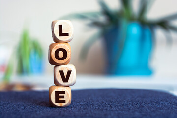 Wooden cubes with the word Love on a colorful blur background. Word of love are made of letters from wood for your girlfriend, boyfriend, for Valentines Day greeting romantic postcard