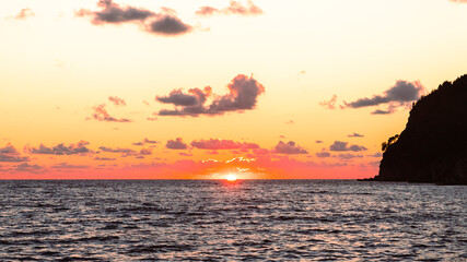 Sunset over the sea. The Sun and beautiful clouds at the horizon