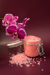Pink bath salt with orchid flower on vinous background