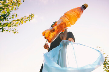 Woman picking the plastic bottle by the garbage picking tool