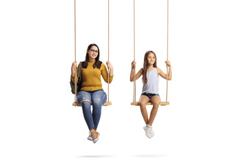 Young female student and a girl sitting on swings and looking at camera - obrazy, fototapety, plakaty