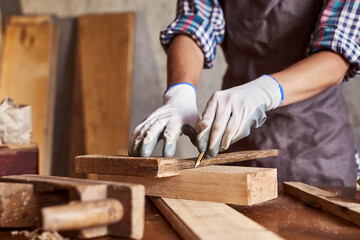 Woman work to making woodcraft furniture in wood workshop. Female carpenter working in carpentry shop with pencil drawing sign on plank. Girl professional high skill workman. - obrazy, fototapety, plakaty