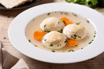 Traditional Jewish matzah ball soup on wooden table. Close up	