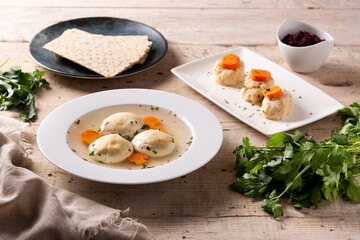 Traditional Jewish matzah ball soup, gefilte fish and matzah bread on wooden table