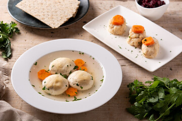 Traditional Jewish matzah ball soup, gefilte fish and matzah bread on wooden table