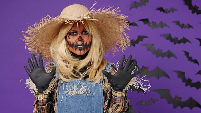 Serious severe young woman with Halloween makeup mask wears straw hat scarecrow costume say no hold palm folded crossed hands in stop gesture isolated on plain dark purple background studio portrait