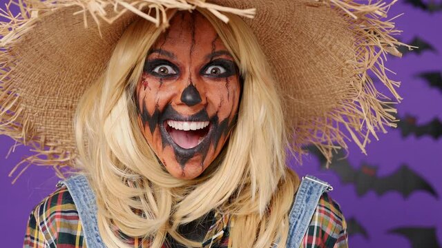 Close up surprised amazed shocked vivid young woman with Halloween makeup mask wears straw hat scarecrow costume looking around say wow yes omg isolated on plain dark purple background studio portrait