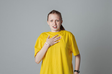 teen girl feeling surprised or shocked, looking at something unexpected, isolated on light grey background, wearing in casual yellow t shirt