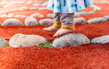Kleinkind balanciert auf Steinen. Gesunde Übung für Füße. Kind übt Gleichgewicht barfuß....