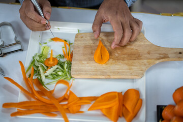 Chef carves patterns on cabbage and other vegetables and fruits for a beautiful table decoration