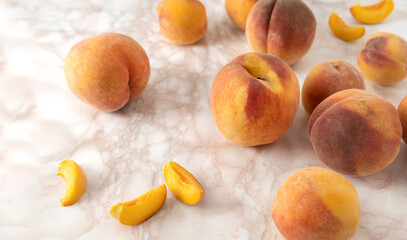 Naklejka na ściany i meble Closeup of slices and whole juicy peaches on the marble table