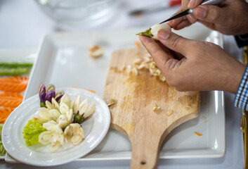 Chef carves patterns on cabbage and other vegetables and fruits for a beautiful table decoration