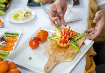 Chef carves patterns on cabbage and other vegetables and fruits for a beautiful table decoration