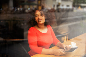 Businesswoman using tablet in cafe. Beautiful woman sitting in cafe, reading the news online.