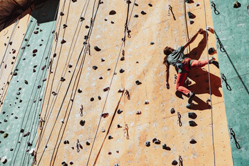 One Caucasian man professional rock climber practicing alone at training center in sunny day, outdoors. Concept of healthy lifestyle, tourism, nature, motion.