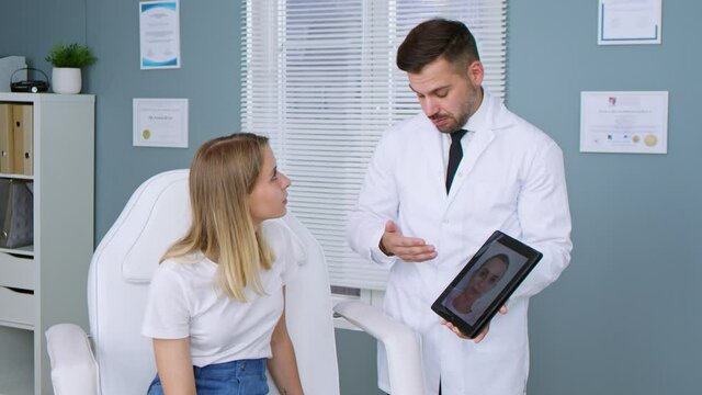 Cosmetic surgeon consulting patient woman about facelift surgery and showing to her digital tablet computer with plan of the future surgery. Medicine concept