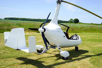 White gyrocopter rear side view canopy open parked on grass runway