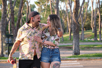 Young cool tattooed couple walking together with a longboard.