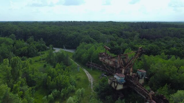 Old abandoned bucket wheel excavator among the trees, aerial view
