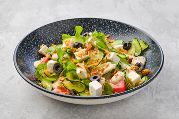 Salad with lettuce, cucumber, olives, tomato, feta and bacon chips