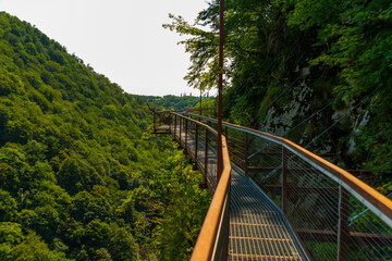 Fototapeta na wymiar OKATSE, GEORGIA: Aerial road in Okatse canyon. All rocks are covered with bright green foliage.