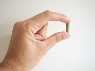 Hand holding of andrographis paniculata capsule on white background. Herbal, medicine, and healthcare concept. closeup photo, blurred.