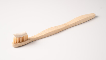 Eco dental concept. Natural toothpaste on a bamboo toothbrush. Wooden toothbrush on white background with copy space